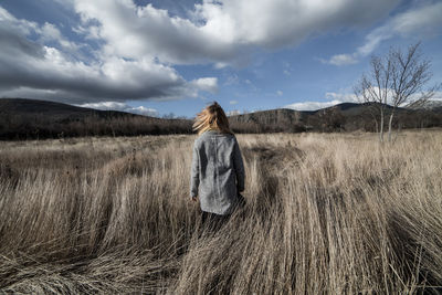 Rear view of woman standing on field against sky