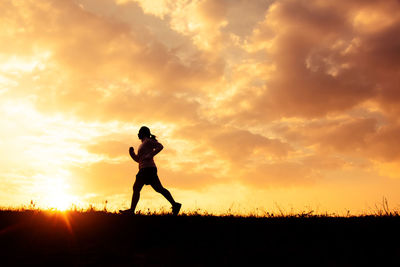 Silhouette man standing on field against sky during sunset