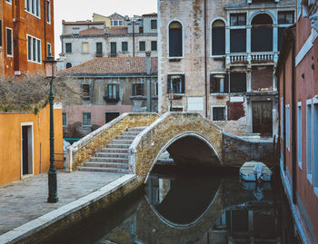 Canal by buildings in city in venice, italy