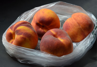 Four peaches in plastic grocery store bag
