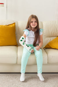 Portrait of young woman sitting on sofa at home