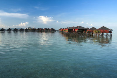 Stilt houses by sea against blue sky