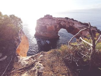 Rock formations on shore against sky