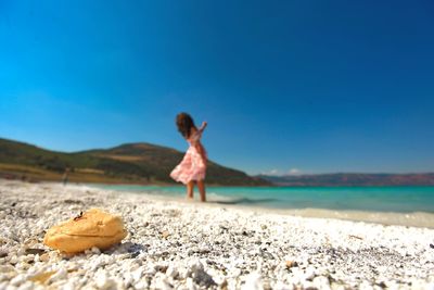 Woman standing on beach against blue sky