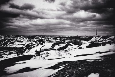 Snow covered landscape against cloudy sky