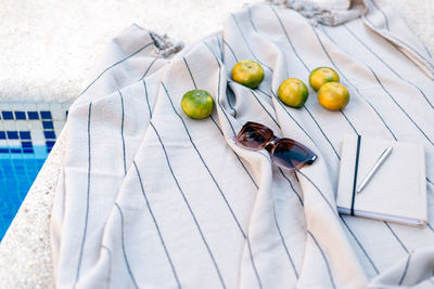 Sunglasses, notebook, pen, and tangerines lie on a picnic blanket by the pool. summer concept.