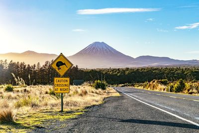 Road sign by mountains against sky