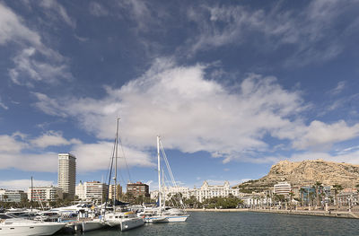 Sailboats moored at harbor against sky