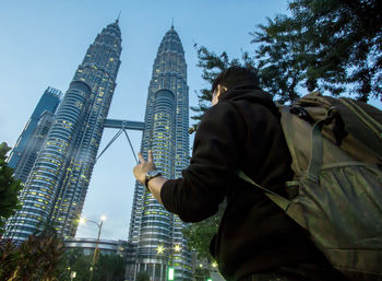 Low angle view of young man standing by petronas towers