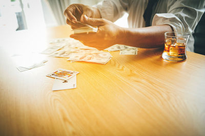 Midsection of man holding playing cards at table
