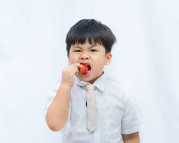 Portrait of cute boy holding ice cream against white background