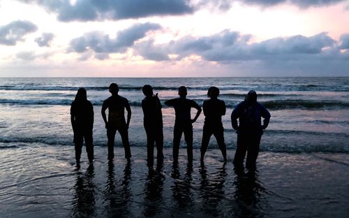 Silhouette people on beach against sky during sunset