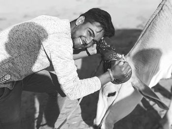 Portrait of smiling man holding cow during sunny day