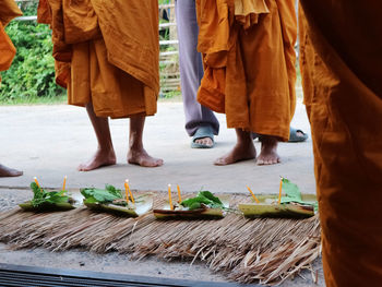 Low section of monks standing by religious offerings on walkway