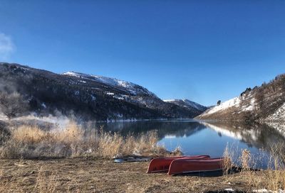 Orange canoes wait in the icy grass along the bear river in idaho