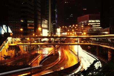 Light trails on road amidst buildings in city at night
