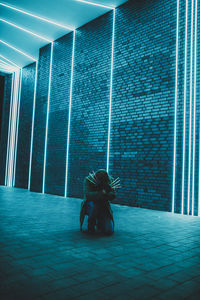 Woman sitting on floor against illuminated wall