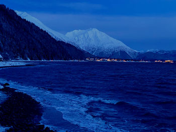 Scenic view of sea and snowcapped mountains against sky