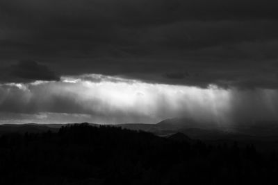 Scenic view of silhouette mountains against storm clouds