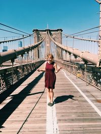 Portrait of happy woman standing on brooklyn bridge during sunny day