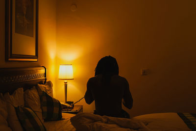 Rear view of man sitting on bed