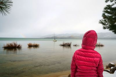 Rear view of woman looking at calm sea against sky