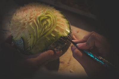 Cropped image of woman making artwork on cantaloupe