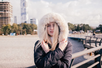 Happy smiling blonde girl is cold in coat with fluffy hood. portrait. high quality photo