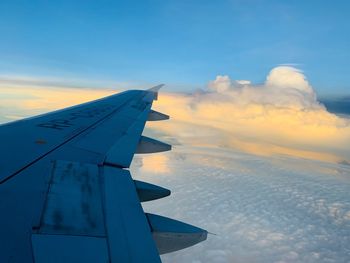 Airplane wing against sky during sunset