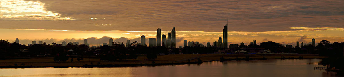 Silhouette of skyscrapers against cloudy sky during sunset