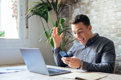 Young man using laptop while sitting on table