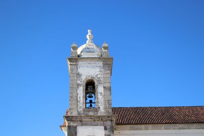 Low angle view of bell tower against clear blue sky