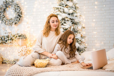 Young woman using phone while sitting on sofa at home