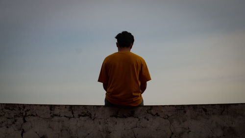 Rear view of man standing against wall