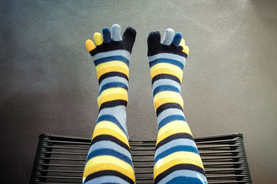 Low section of person colorful striped socks while sitting on chair