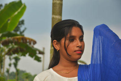 Portrait of young woman looking away against sky