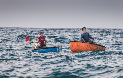 People on boat in sea against clear sky