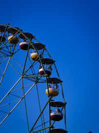 Low angle view of ferris wheel against clear blue sky