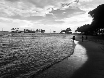 People on beach against sky in city