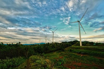 Wind turbines on field against sky