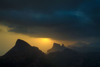 View of rocky mountains against cloudy sky at sunset