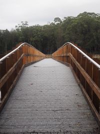 Footbridge amidst trees against sky