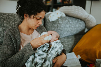 Close-up mother feeding baby milk with bottle