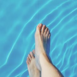 Low section of woman relaxing in swimming pool