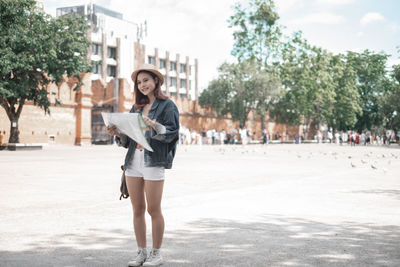 Full length portrait of smiling woman in city