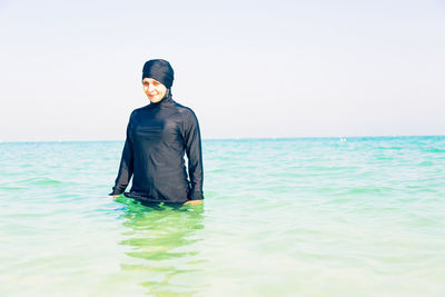 Young woman standing in sea against clear sky