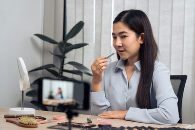 Young woman using phone while sitting on table