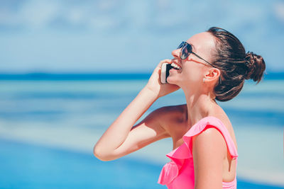 Side view of young woman looking at sea against sky