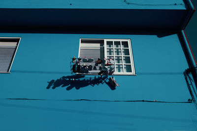 Low angle view of shoes drying by window of house during sunny day