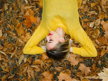 High angle portrait of woman lying down on autumn leaves